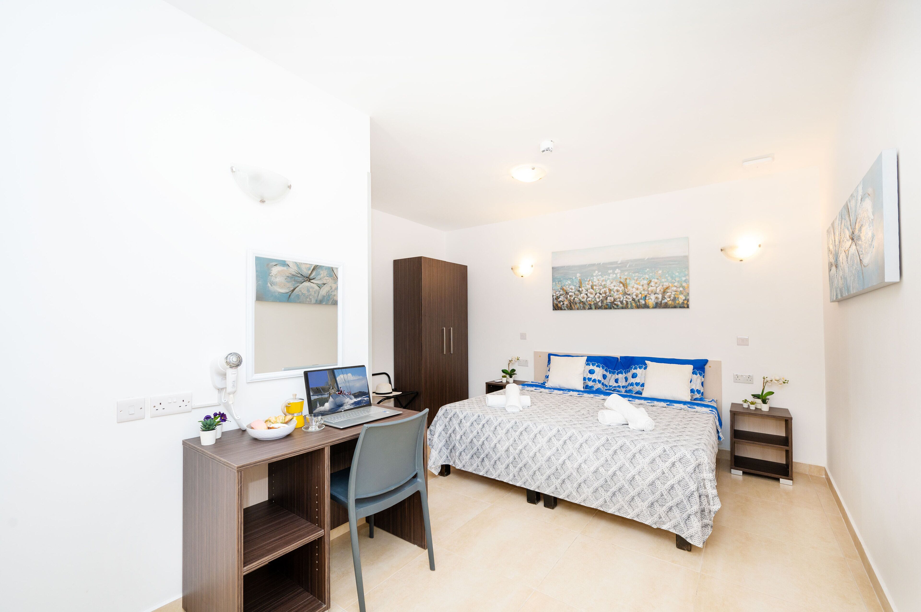 Une chambre moderne avec un lit, un bureau, une chaise et une petite table de chevet.