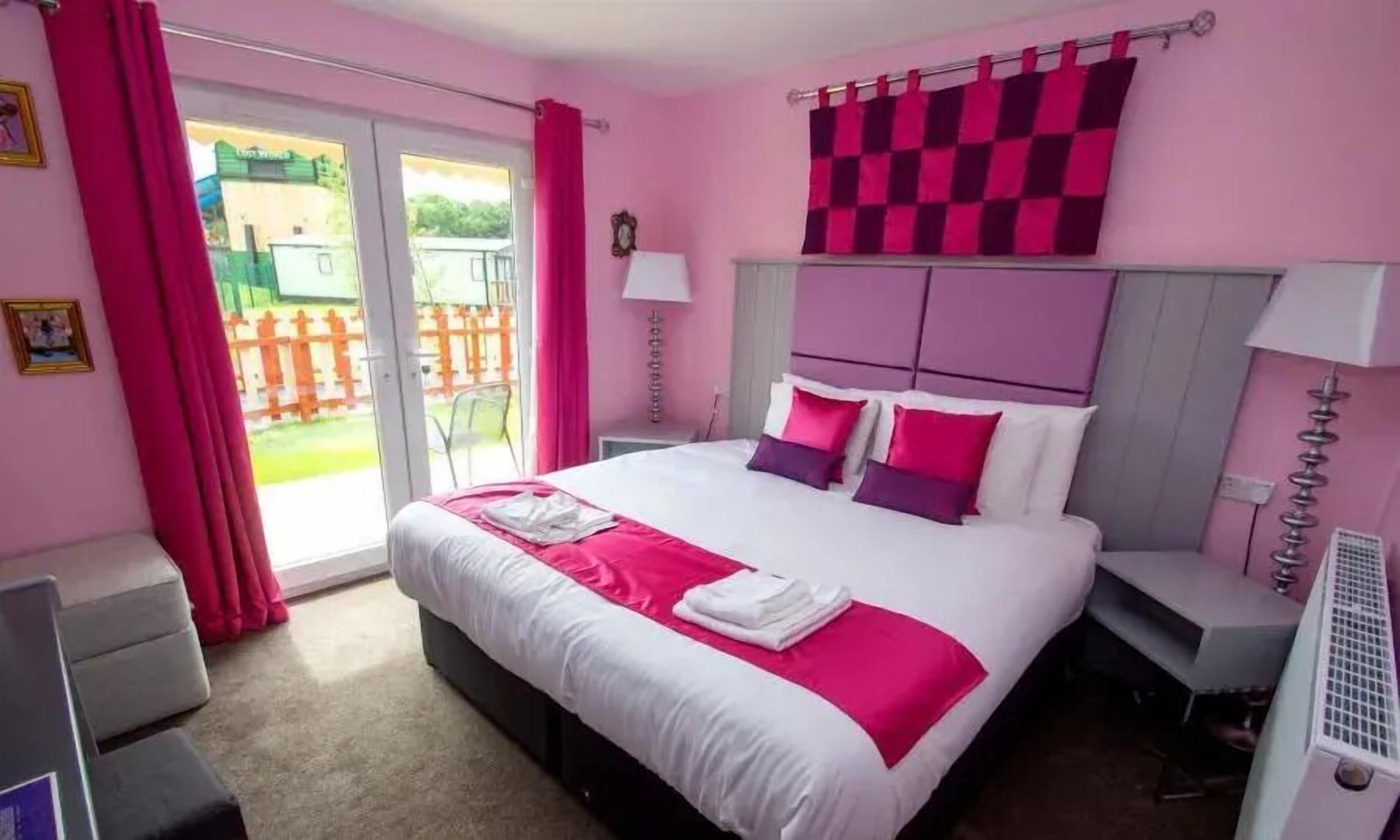 A bedroom with a bed, a desk, a chair, a radiator, and a window with curtains.