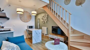 Una sala de estar moderna con una escalera, un comedor y una cocina.