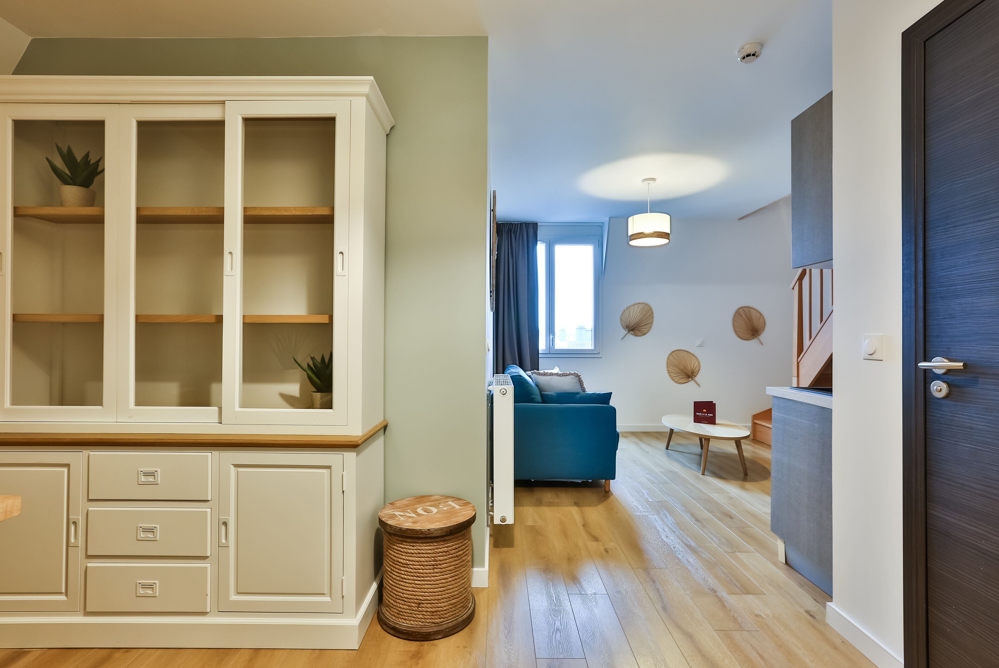 Una sala de estar moderna con un sofá azul, una pequeña mesa redonda y un mueble con cajones.