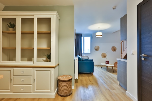 Una sala de estar moderna con un sofá azul, una pequeña mesa redonda y un mueble con cajones.
