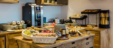 A buffet setup with various food items, a coffee machine, and shelves with kitchenware.