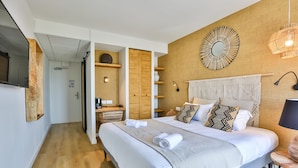 A modern bedroom with a large bed, wooden headboard, and a wall-mounted mirror. - Hôtel Spa Face à la Mer (Merville-Franceville-Plage)