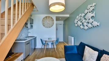 Un espacio habitable moderno con escalera, comedor y sofá azul.