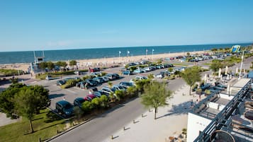 A hotel with outdoor seating overlooking a beach and parking area.