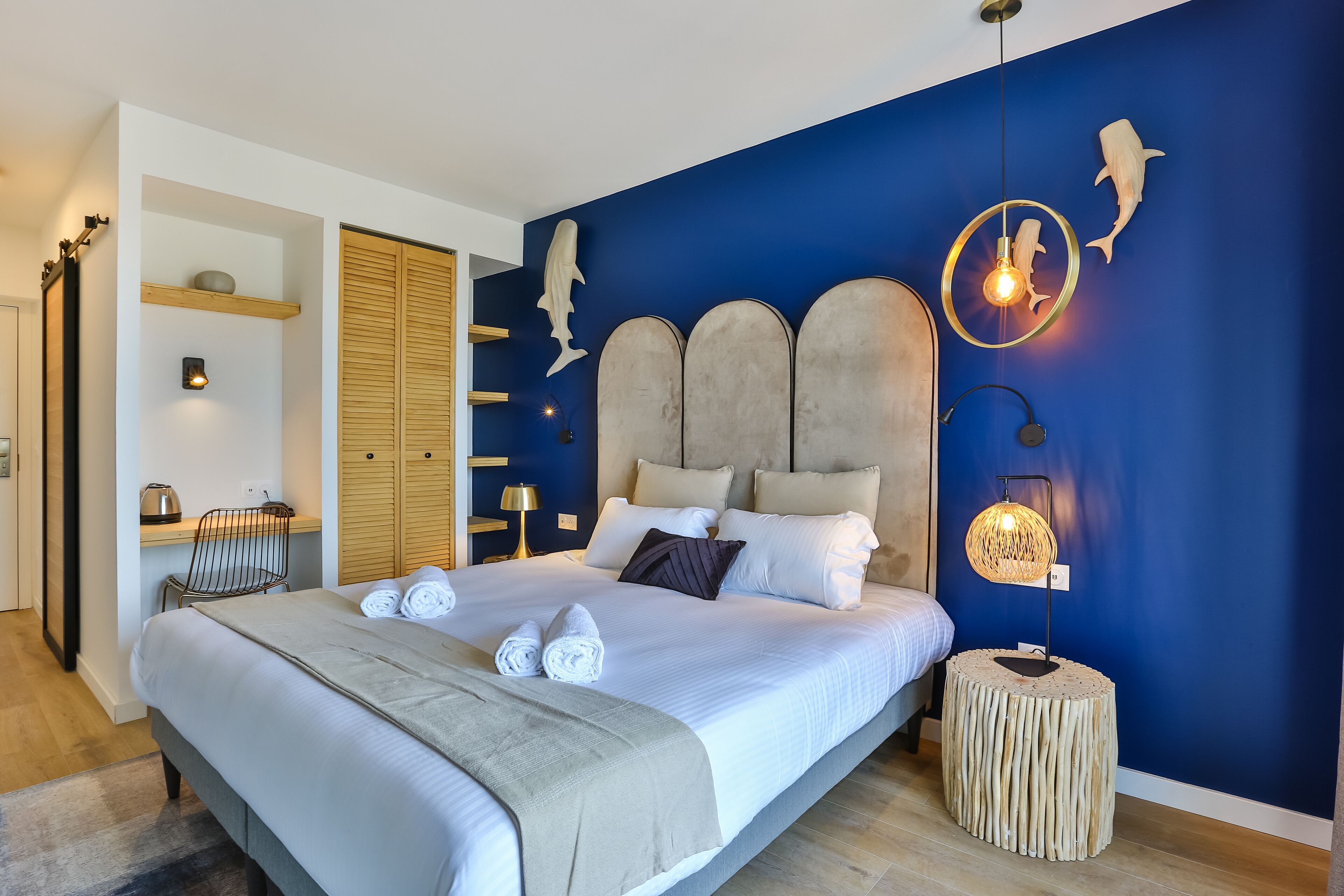 A modern bedroom with a large bed, wooden headboard, and decorative wall art.