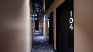 A hallway with a dark floor, beige walls, and black doors with numbers.