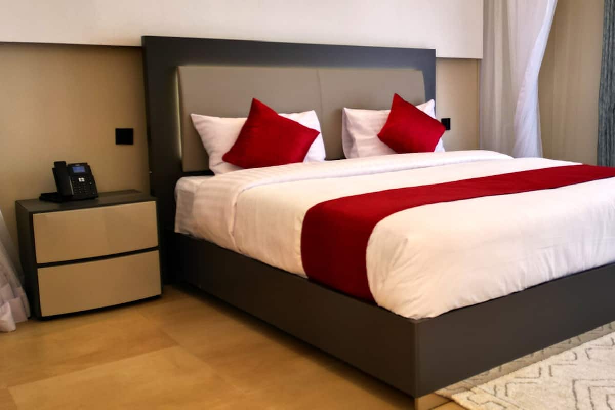 Una habitación de hotel moderna con una cama grande, un teléfono en la mesita de noche y una mesita auxiliar.