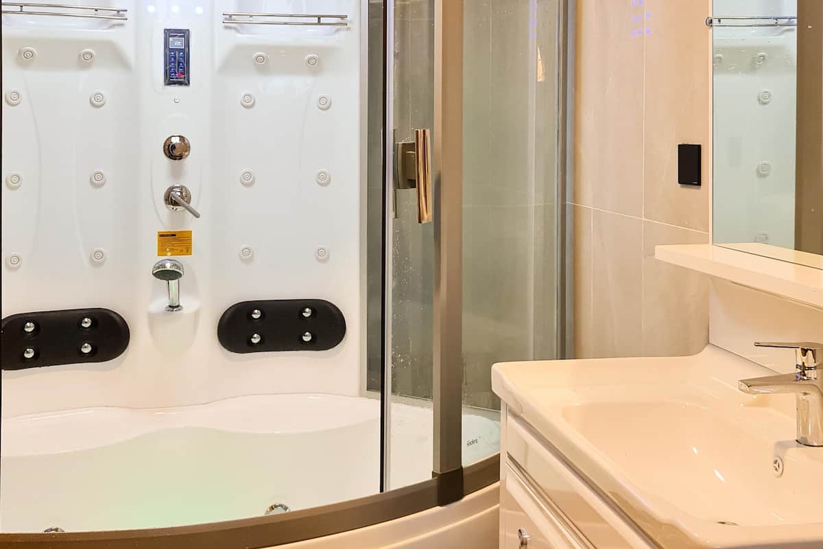 Un baño moderno con ducha de vidrio, lavamanos blanco y espejo.