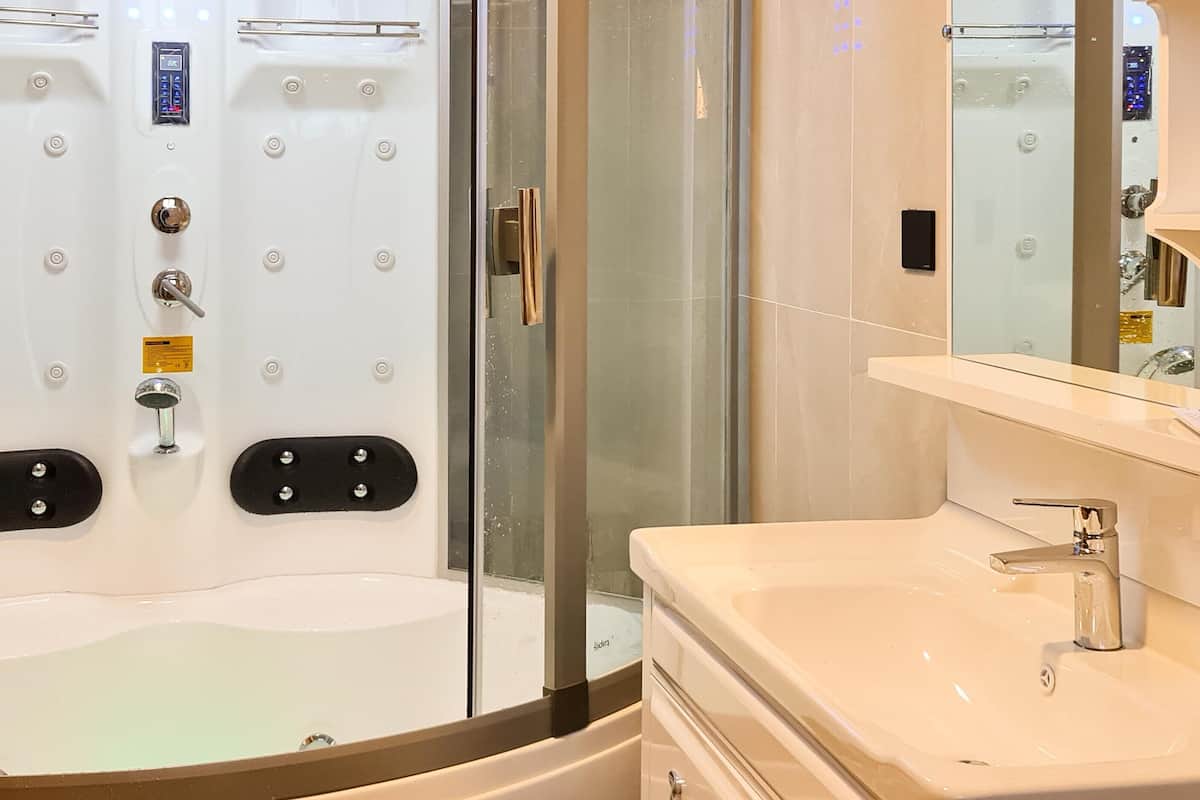 Un baño moderno con cabina de ducha de vidrio, un lavamanos blanco y un espejo.