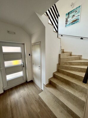 Staircase leads to a landing with a door and a wall-mounted light fixture.