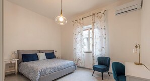 Une chambre à coucher comprenant un lit, un bureau, une chaise et un luminaire suspendu.