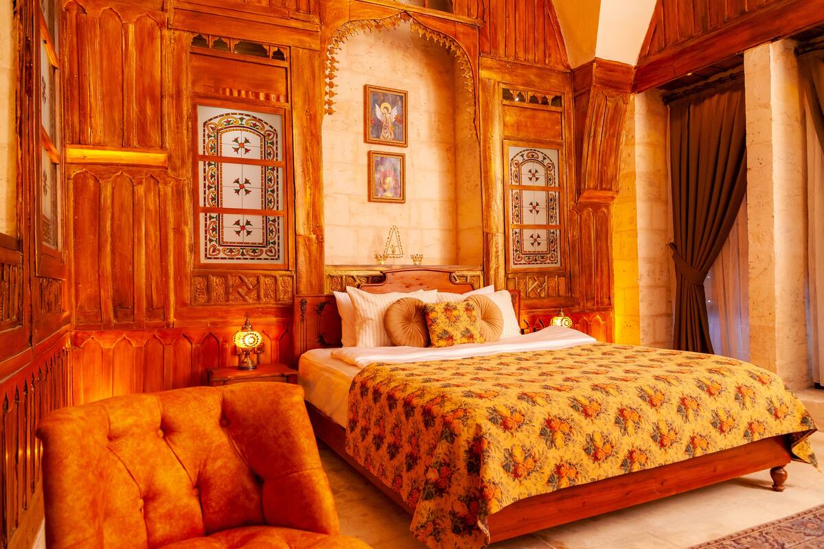 A traditional bedroom with a large bed, ornate wooden paneling, and a chandelier.