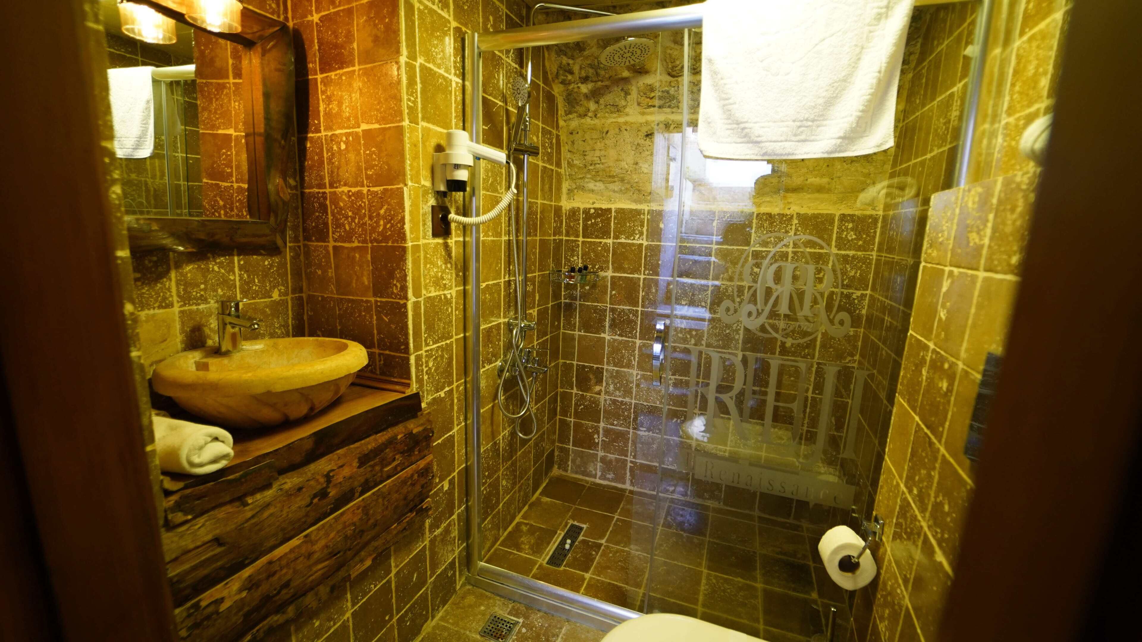 A bathroom with a wooden vanity, a sink, a glass-enclosed shower, and a toilet.