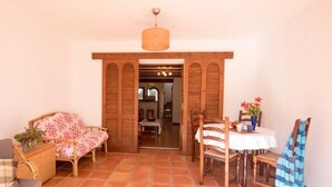 A cozy room with a wicker sofa, a dining table with chairs, and a wooden door leading to another room. - Apartment Sol de Denia. Wifi, A/C (Dénia)