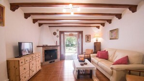 A living room with a fireplace, a sofa, a television, and a wooden cabinet. - Apartment Sol de Denia. Wifi, A/C (Dénia)