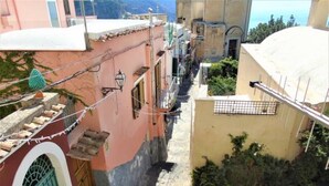 Uma rua estreita com edifícios de ambos os lados, um portão e plantas em vasos.