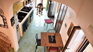 Uma cozinha com área de refeições, uma mesa de madeira com cadeiras e vista para a área de jantar através de um arco.