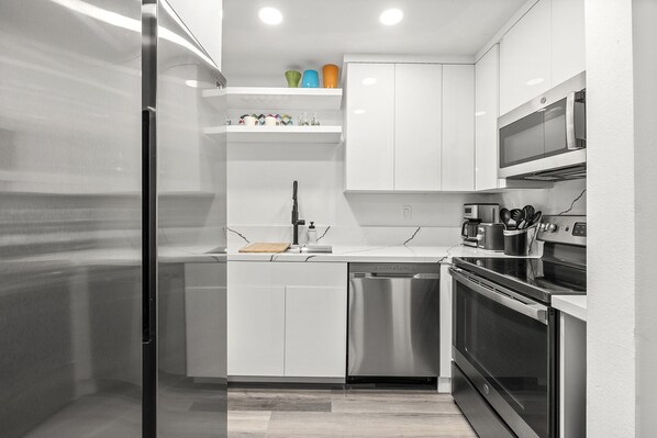 A modern kitchen with white cabinets, stainless steel appliances, and a microwave above the stove.