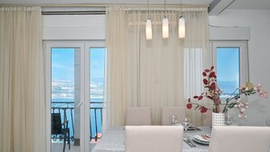 Un comedor con vista al mar, una mesa para dos y un jarrón con flores.