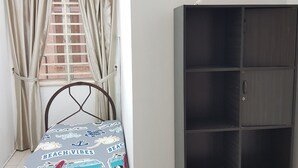 Un dormitorio con cama, ventana con cortinas y un armario.