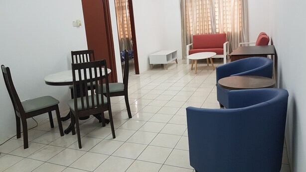 Una sala de estar con una mesa de comedor, dos sillas, un sofá y un mueble para televisión.