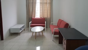 Una sala de estar con un sofá rojo, un sillón blanco, una mesita blanca y un sofá cama rojo.