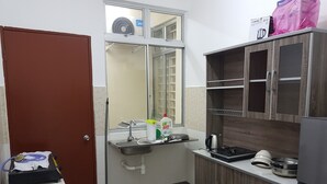 Una cocina pequeña con un lavamanos, armarios y una ventana con ventilador.