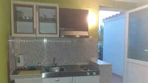 Una cocina compacta con armarios blancos, salpicadero de azulejos y estufa integrada.