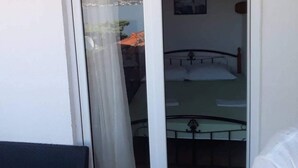 Una habitación con una cama, un ventanal con vista a la montaña y una puerta que da a otra habitación.