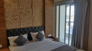 Habitación de hotel con una cama grande, cabecera de madera y vista al exterior mediante una puerta corrediza de vidrio.