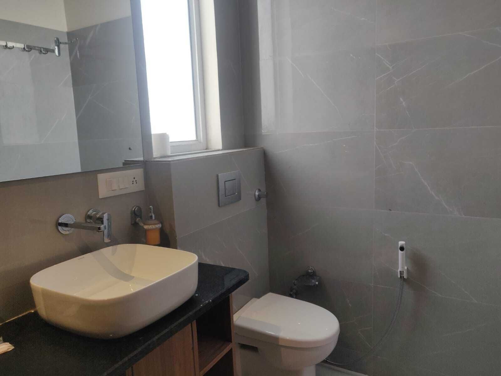 A modern bathroom with a large sink, toilet, and a mirror above the sink.