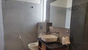 Un baño moderno con inodoro, lavamanos y espejo.