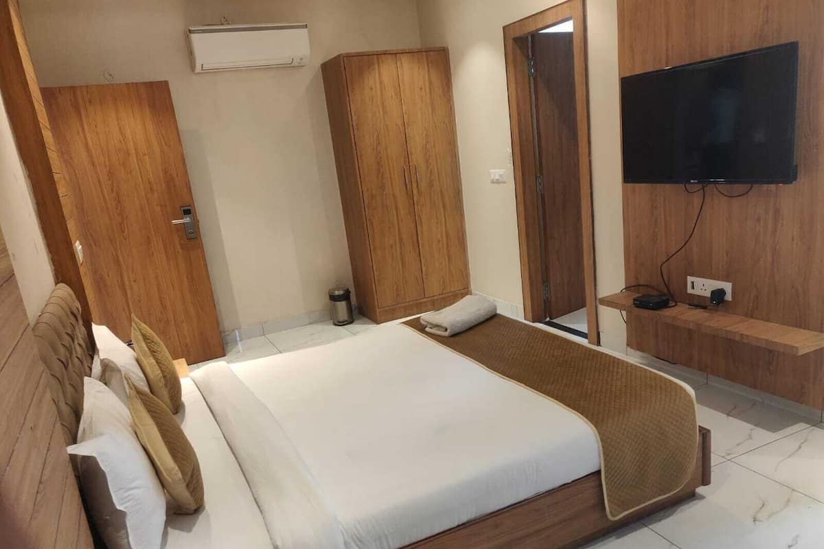 Un dormitorio con cama, armario de madera, televisor y una pequeña mesa.