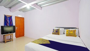 A bedroom with a bed, a television on a stand, and a door. - Hotel O Biring Residence (Wargasaluyu)