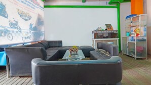 A modern living area with a sectional sofa, a glass coffee table, and a decorative item on the table. - Hotel O Biring Residence (Wargasaluyu)