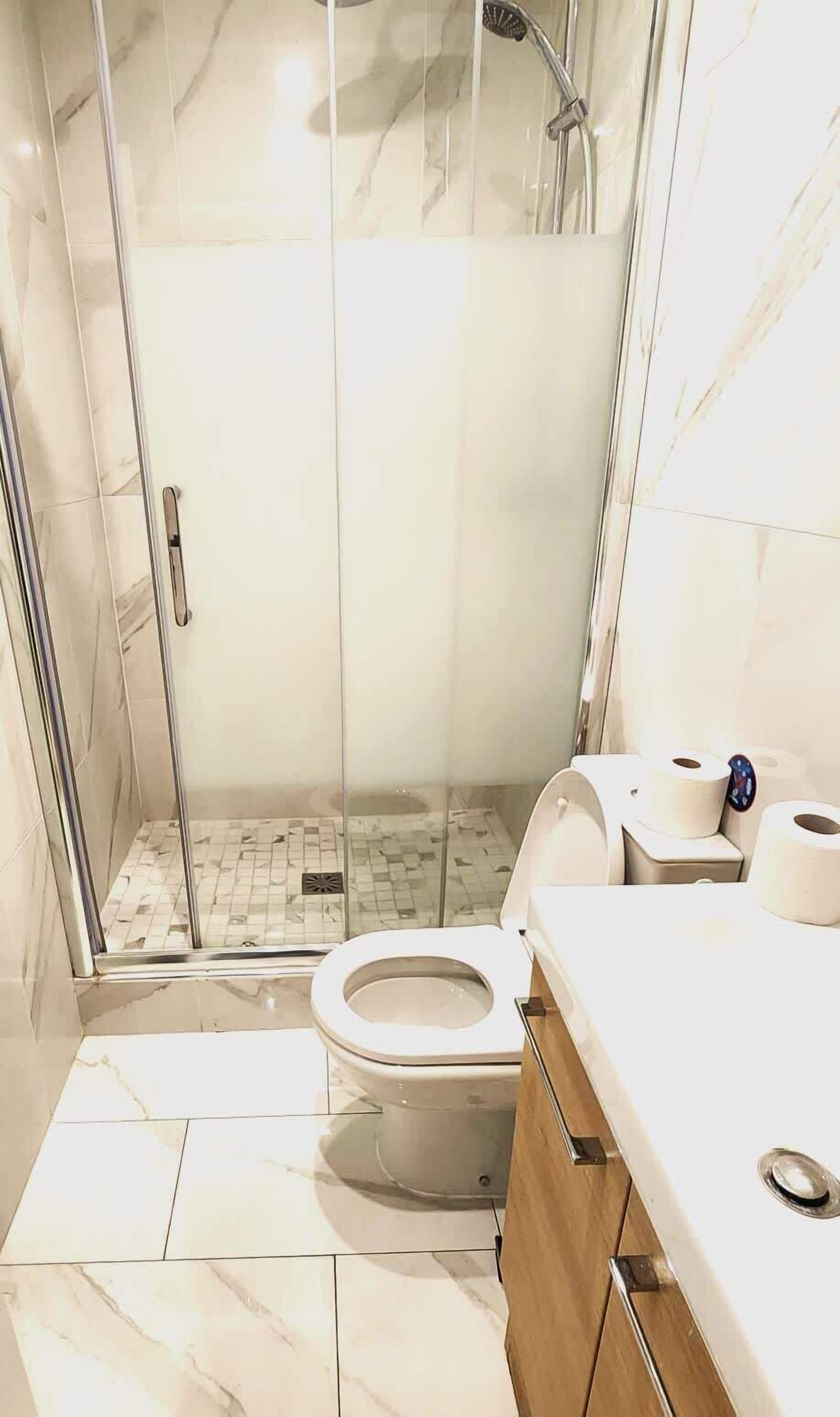 Une salle de bain moderne avec une douche à parois de verre, des toilettes et un meuble-lavabo avec un miroir.