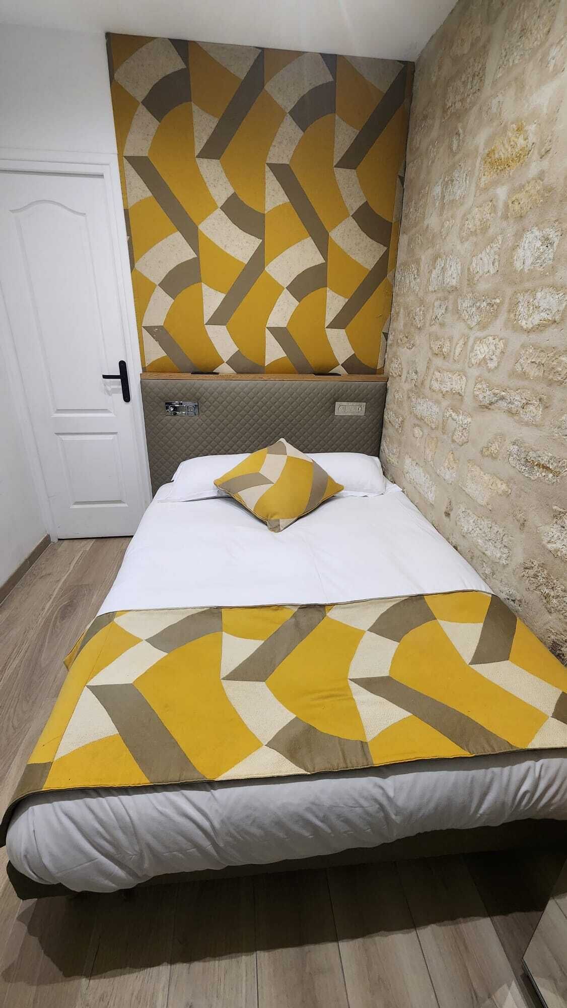 Een slaapkamer met een bed, een kussen, een hoofdbord, een deur en een gestructureerde muur.