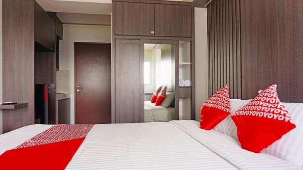 A modern hotel room with a large bed, a wardrobe, and a mirror.
