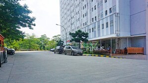 A parking area in front of a building with a sign reading "TOWER PIKUS".