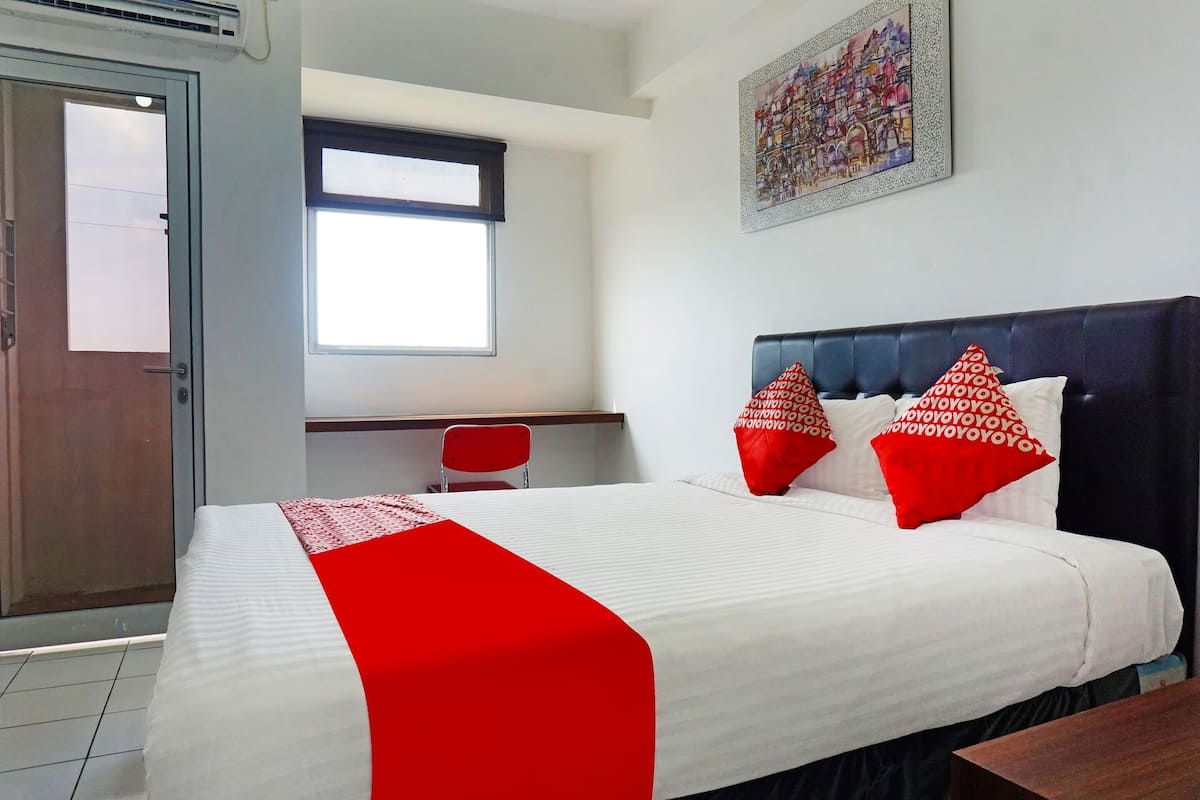 Una habitación de hotel con cama, escritorio, silla y ventana.
