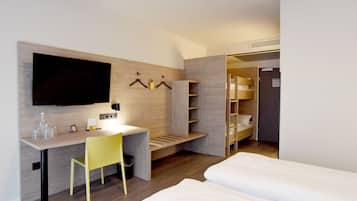 A modern hotel room with a wooden desk, a television, a bed, and a wardrobe.