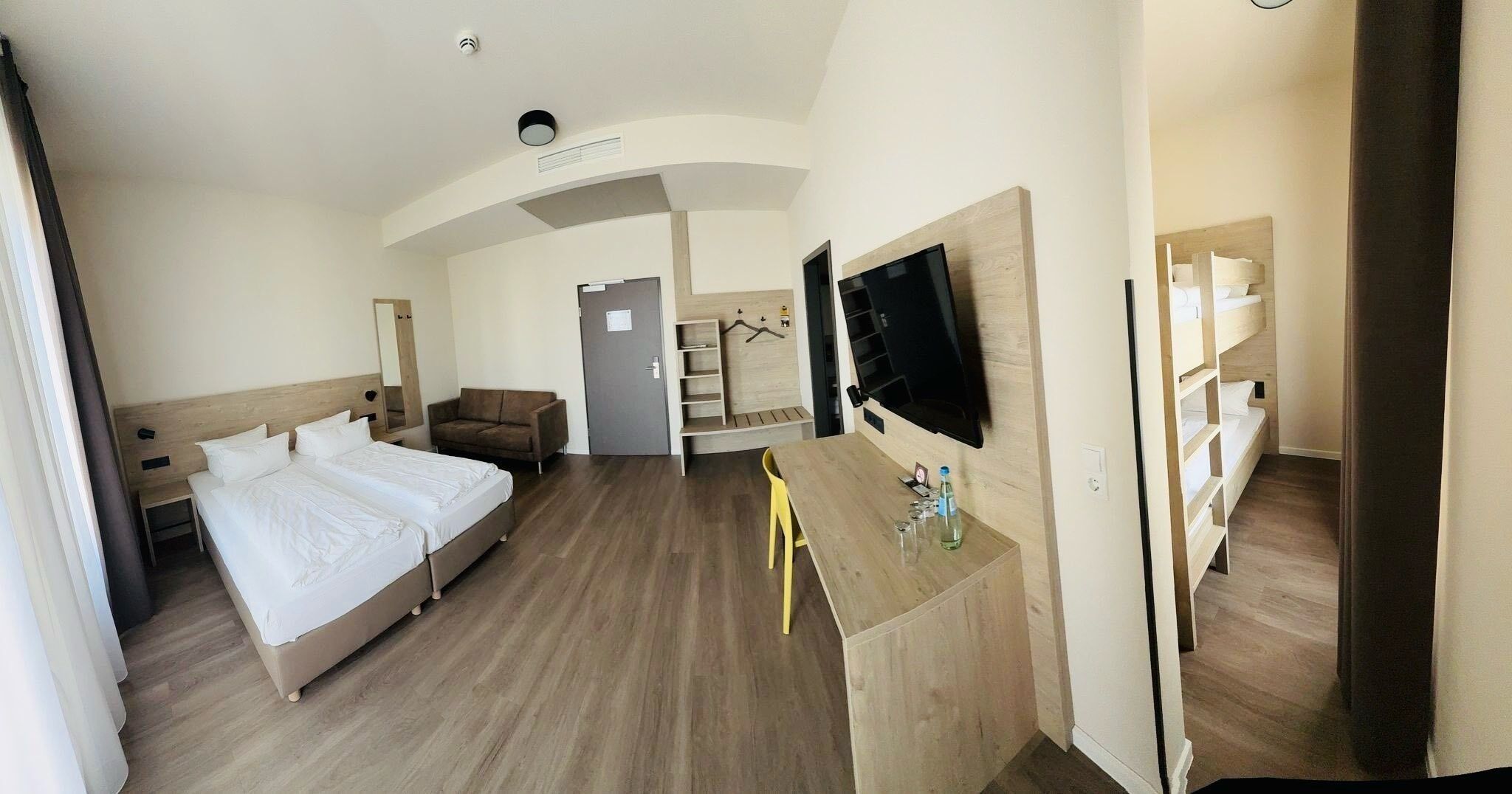 A hotel room with two beds, a TV, a desk, and a chair.