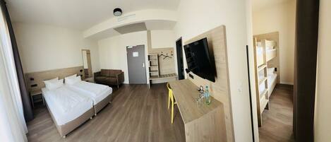 A hotel room with two beds, a TV, a desk, and a chair.