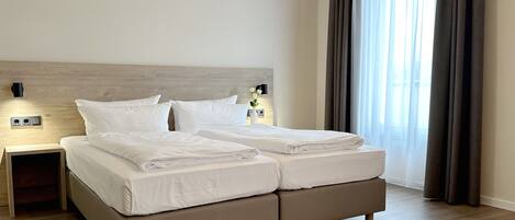 A double bed with a wooden headboard, a nightstand, and a wall-mounted light.
