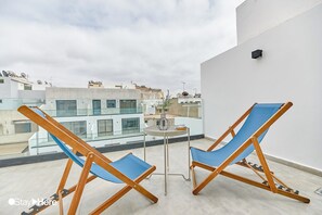 A balcony with two blue lounge chairs and a small table. - StayHere Casablanca - Gauthier Loft Living (Casablanca)