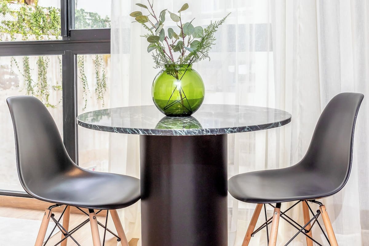 A modern room with a round table, two chairs, and a green vase with plants.