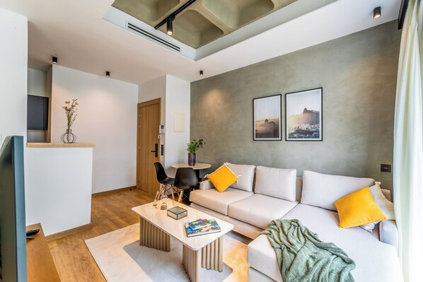 A modern living room with a sofa, coffee table, and chairs. There is a small table with a vase and a plant. Two framed pictures are on the wall. - Stayhere Casablanca - Gauthier Loft Living (Casablanca)