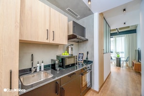A modern kitchen with stainless steel appliances, wooden cabinets, and a dining area with a table and chairs. - Stayhere Casablanca - Gauthier Loft Living (Casablanca)