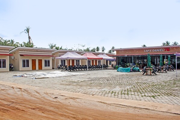 A courtyard with outdoor seating, palm trees, and a building labeled "Café Daniel 76".